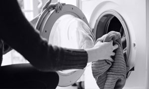 Woman adding items to washing machine.